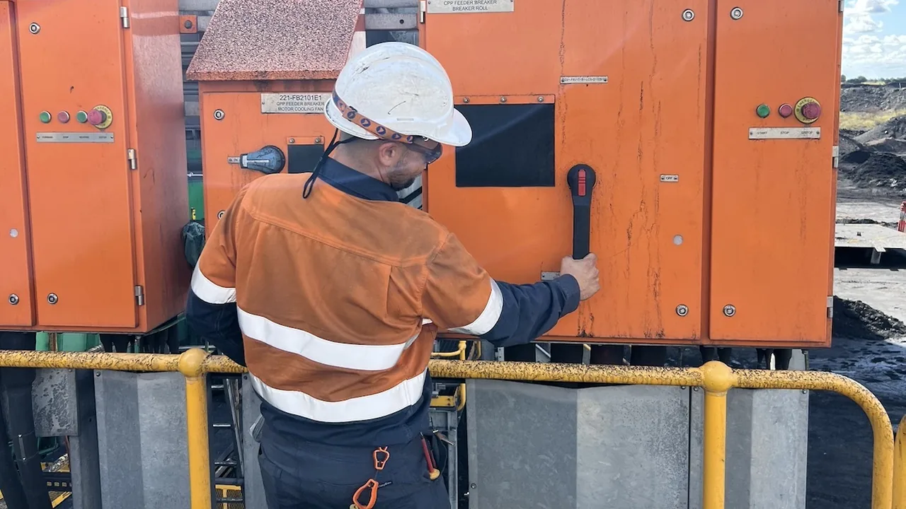 Electrician operating an isolator on a coal plant feeder breaker switchboard